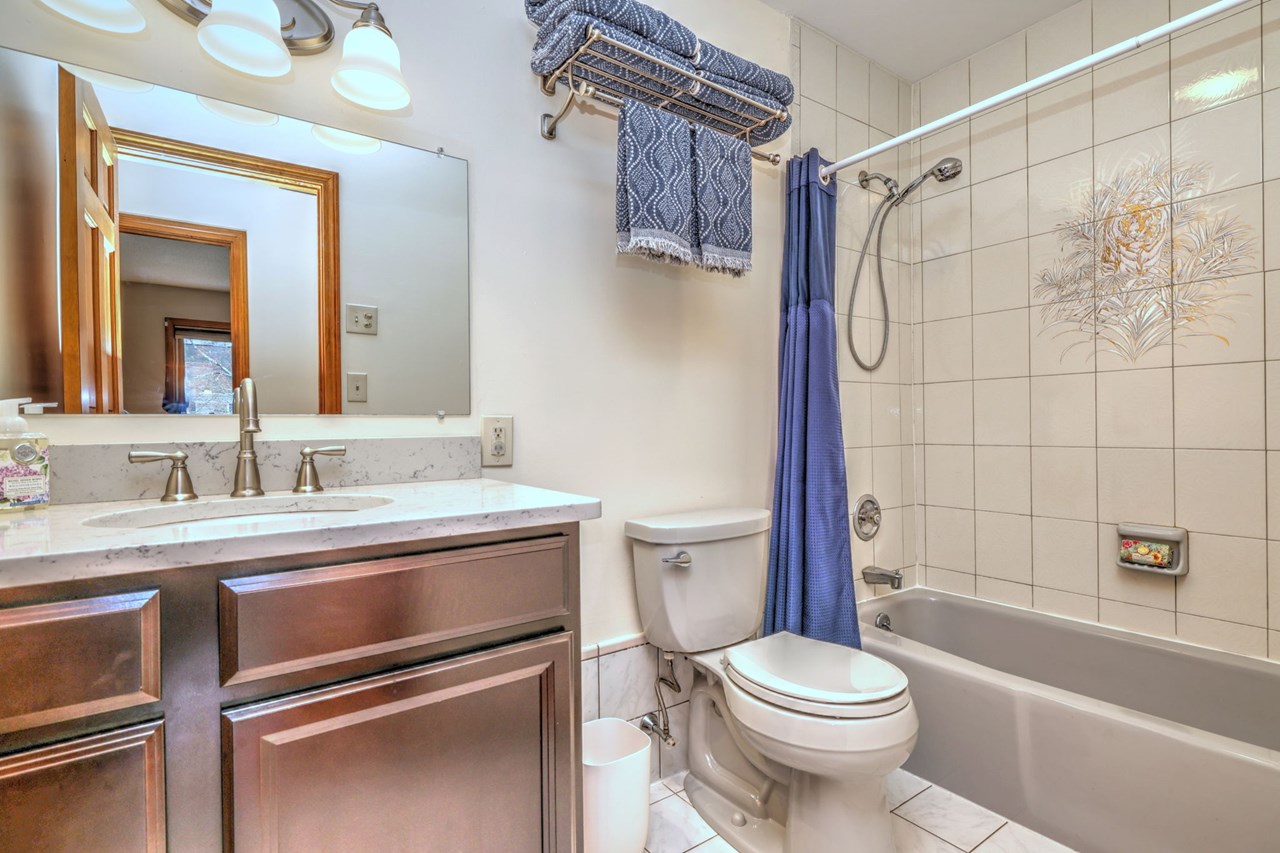 natural light pours in from above in this hall bath with quartz countertops.